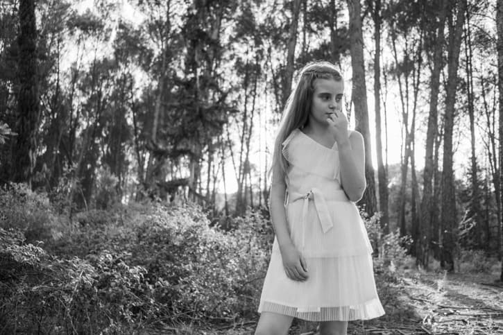 Fotografía en blanco y negro de una niña pequeña en su comunión en el bosque
