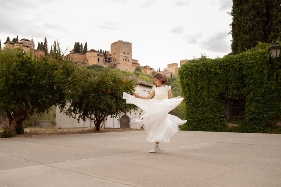 Fotografía de una niña de comunión con la Alhambra de fondo