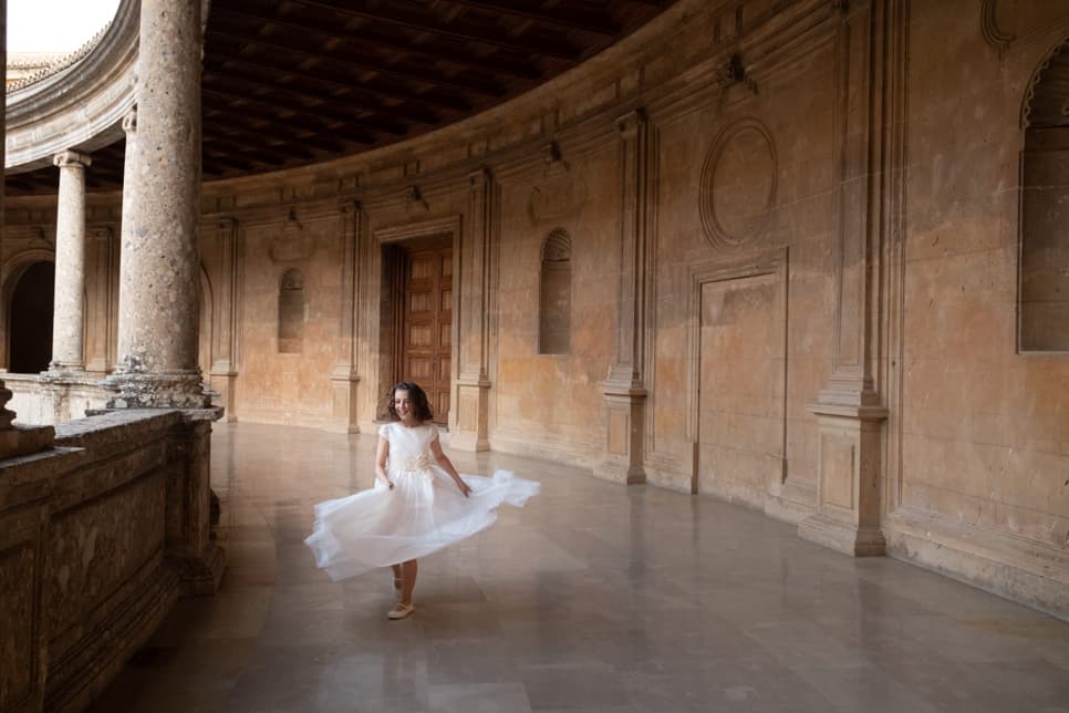 Fotografía de una niña de comunión con un vestido blanco caminando en un coliseo