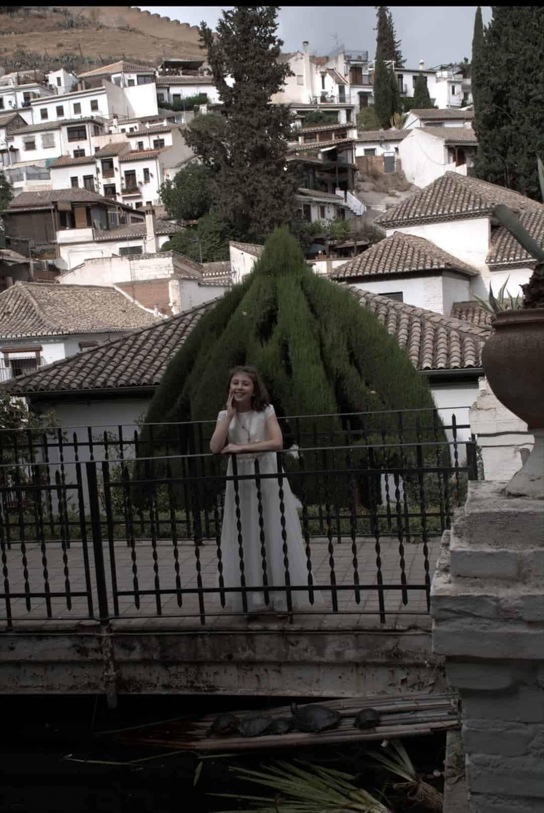 Fotografía de una niña de comunión en el Albaicín de Granada apoyada en una barandilla