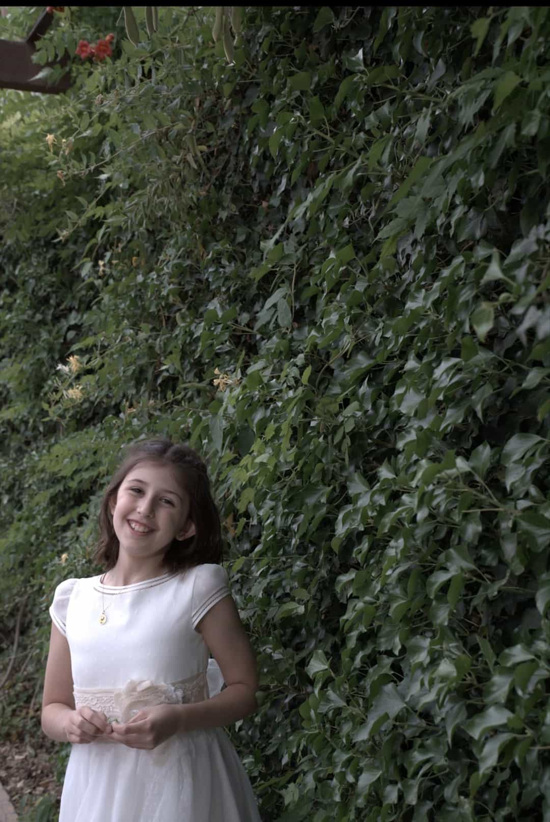 Fotografía de una niña de comunión en un jardín de Granada mientras sonríe