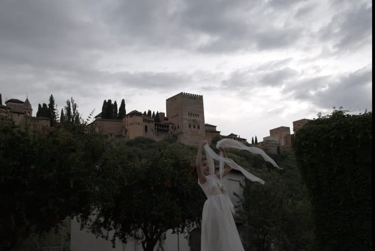 Fotografía de una niña de comunión feliz con la Alhambra de fondo en Granada