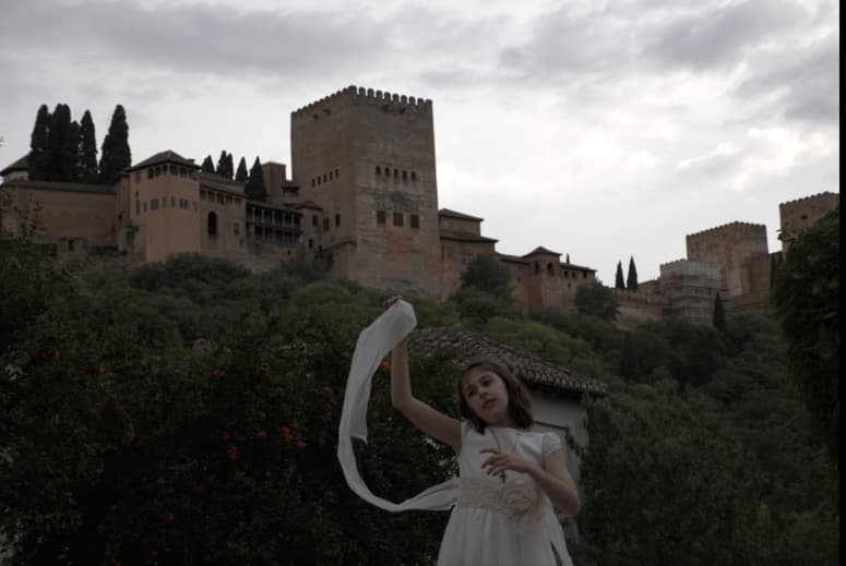 Fotografía de una niña de comunión con la Alhambra de Granda de fondo en un día nublado
