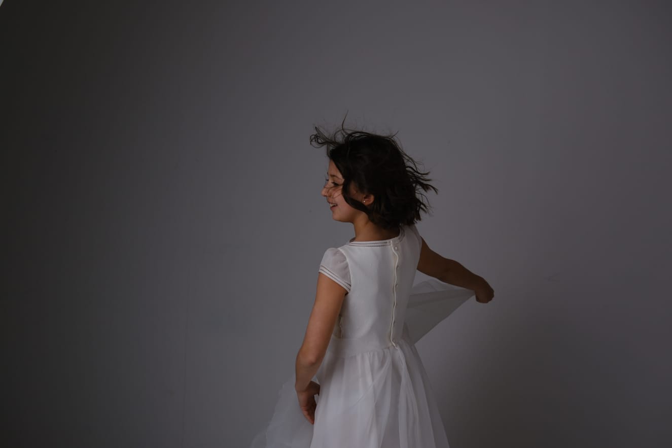 Fotografía de una niña de comunión de espaldas con un vestido blanco