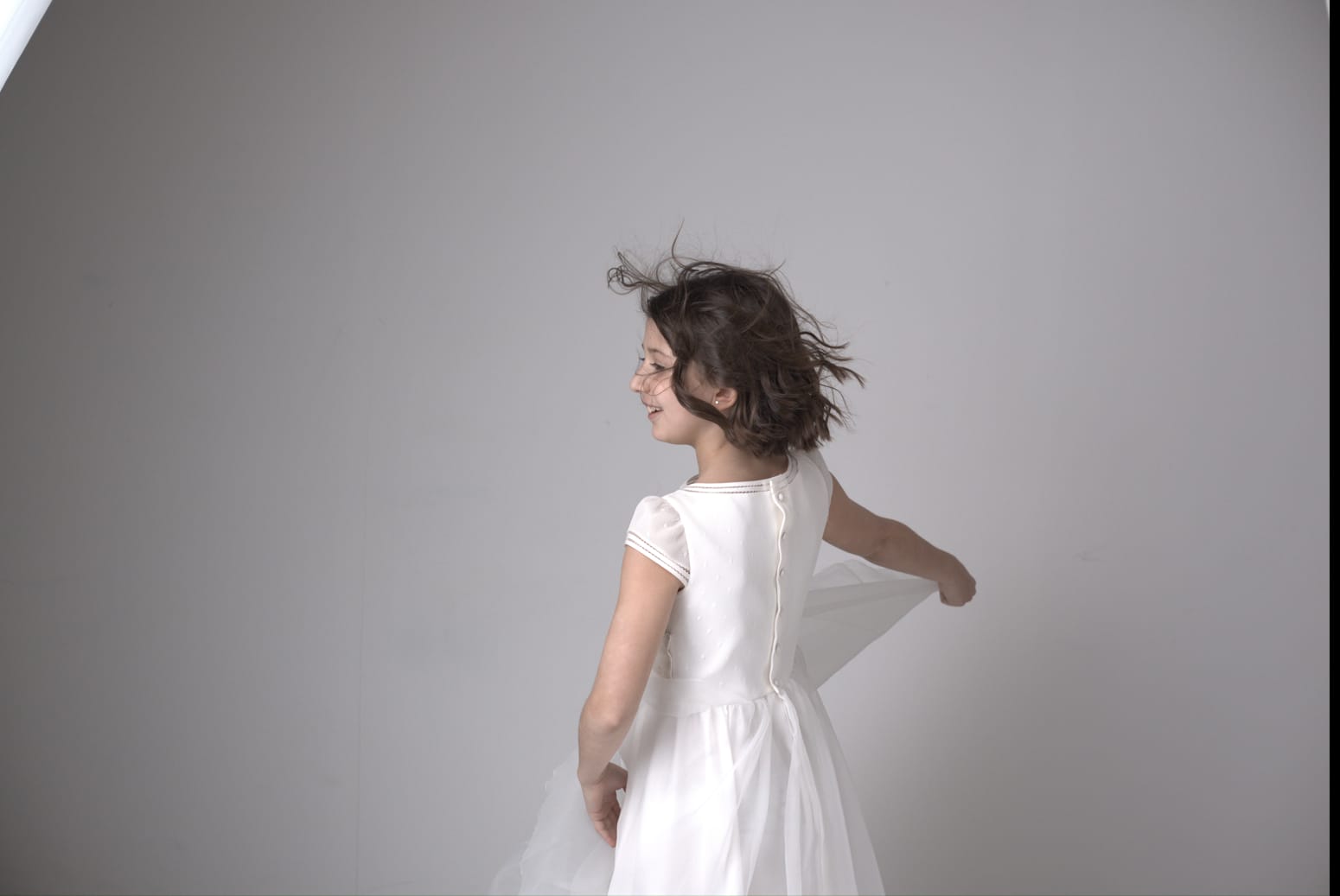 Fotografía de una niña de comunión sujetando su vestido y mirando de espaldas a la cámara